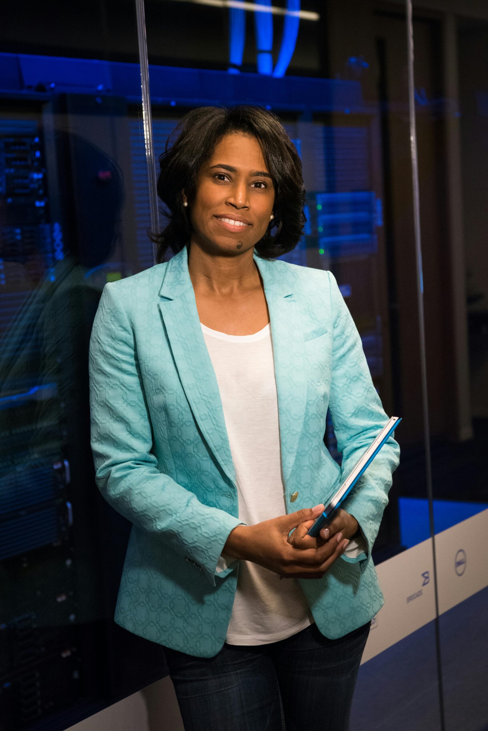 Confident woman in a server room, holding a tablet. Ideal for tech and business themes.