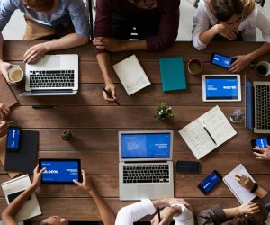 Overhead view of a diverse team in a business meeting using laptops and tablets.